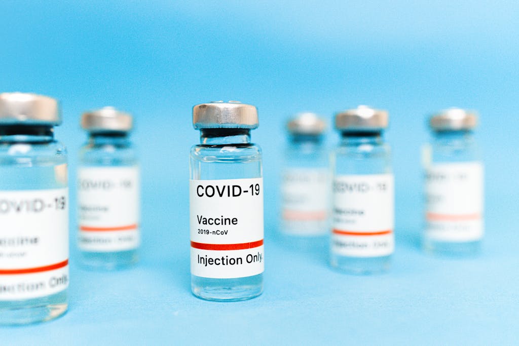 Close-up image of Covid-19 vaccine vials with labels on a light blue background.