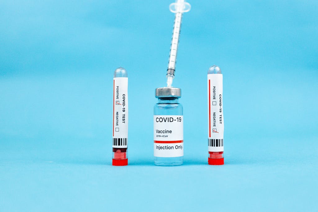 Close-up of COVID-19 vaccine vial and test tubes on a blue background, highlighting immunization and testing.